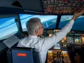 Doświadczony pilot w kokpicie, dotykający panelu sterowania. To inspiracja, jak zostać pilotem samolotu i osiągnąć marzenia o lataniu.