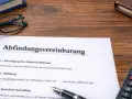 Abfindungsvereinbarung-Muster kostenlos: Dokument mit Klauseln zur Beendigung des Arbeitsverhältnisses und Abfindungshöhe, daneben Brille, Buch und Taschenrechner.