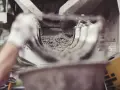 Ręka w rękawiczce kieruje strumień cementu do maszyny. Zastanawiasz się, ile kosztuje worek cementu?