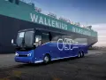 Niebieski autokar Van Hool CX45 z napisem "ZERO EMISSIONS" stoi przy ogromnym statku Wallenius Wilhelmsen.