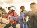 Trois randonneurs souriants, prêts pour une reconversion accompagnateur moyenne montagne, profitent du soleil couchant sur les sentiers.