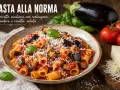 Pyszne danie pasta alla norma z bakłażanem, pomidorami i ricottą salata, posypane startym serem.