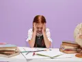 Une petite fille rousse, les mains sur la tête, semble dépassée par ses devoirs. La scène évoque les défis de la réglementation du dortoir maternelle.
