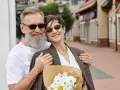 Uśmiechnięta para seniorów z bukietem kwiatów. Ich miłość trwa już 45 lat, czyli właśnie obchodzą rubinowe gody.