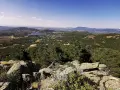 Vista panorámica del valle de la barranca, con un lago azul y montañas verdes bajo un cielo despejado.