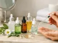 Des flacons de sérum pour visage, dont un est appliqué sur la main, illustrent à quoi sert le sérum pour visage : hydrater et nourrir la peau.