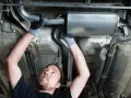 Mechanic working on a car's exhaust system. This tune up consists of replacing a section of the exhaust pipe and muffler.