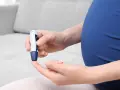 Kobieta w ciąży wykonuje pomiar glukozy glukometrem. Dba o swoją krzywą cukrową.