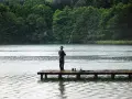 Ein Angler steht auf einem Steg und übt aus, wie angelt man, während es regnet.