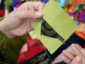 Ręce szyją zielone kwadraty z czarnym wzorem, tworząc patchwork projekty.