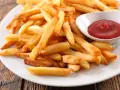 Une assiette de frites au four dorées et croustillantes, accompagnées d'un petit bol de ketchup rouge vif.
