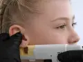Dziewczynka z warkoczem przygotowuje się do przekłucia ucha. Zastanawia się, gdzie najbardziej boli kolczyk w uchu.