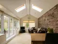 Salon lumineux avec murs en briques apparentes, baies vitrées donnant sur jardin. Idéal pour estimer le prix d'une extension 20m2 en parpaing.