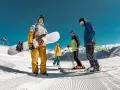 Grupa przyjaciół cieszy się jazdą na nartach i snowboardzie w marcu. Słońce świeci, a śnieg jest idealny do zjazdów.