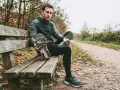 Runner seduto su una panchina controlla le sue scarpe da corsa, pensando a ogni quanto cambiarle per non incorrere in infortuni.