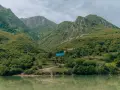 Zielone góry nad jeziorem, z domami i niebieskim dachem.