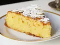 Rebanada de tarta de almendra esponjosa, espolvoreada con azúcar glas y láminas de almendra.