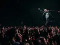 Wokalista Three Days Grace Polska na scenie, z tłumem fanów nagrywających koncert telefonami.