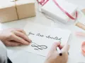 Ręce piszą zaproszenie "You Are Invited". Dowiedz się, jak napisać zaproszenie na urodziny po angielsku.