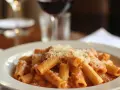 En tallrik rigatoni med krämig tomatsås och parmesanost, perfekt till ett glas vin eller en vodkapasta.