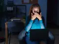 Kobieta zszokowana treścią na laptopie, czuje się jakby była obiektem prześladowania kogoś.