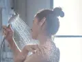 Donna sotto la doccia, l'acqua della doccia esce alternativamente calda e poi fredda, creando un effetto rinfrescante.