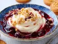 Ein edler Nachtisch: Cremiges Dessert mit Kirschkompott und Keksbröseln in einer blauen Schale, daneben Butterkekse.