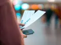 Dłoń trzyma bilety lotnicze i paszport. Może to być sytuacja związana z planowaniem podróży lub procesem **Ryanair zwrot biletu**.