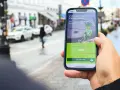 Dłoń trzyma telefon z aplikacją Vivus, gdzie można złożyć wniosek o pożyczkę. W tle miejski krajobraz. Vivus windykacja pomaga spełniać marzenia.