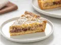 Una fetta di torta ricotta e cioccolato cosparsa di zucchero a velo su un piatto bianco.