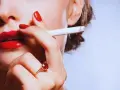 Labios rojos, uñas rojas y un cigarrillo. Una mujer se lleva el cigarrillo a la boca, quizás pensando que la nicotina adelgaza.