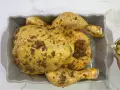 Un pollo al ast, sazonado y listo para hornear, recibe un chorrito de aceite para una cocción perfecta.