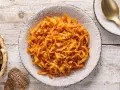 Un saporito cappuccio stufato in padella, servito in un piatto rustico, accompagnato da pane scuro e una posata dorata.