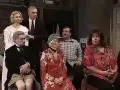 Scena z filmu "Tango" Mrożka. Grupa osób siedzi i stoi w pomieszczeniu.