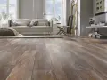 Sala de estar moderna con suelo de tarima AC5 de aspecto madera desgastada, sofá beige, alfombra y pufs.