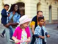 Glückliche Familie unterwegs: Mutter trägt Kind, Vater schiebt Roller. Ein Spagat zwischen Kind und neuem Partner gelingt hier spielerisch.