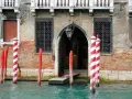 I pali di Venezia, chiamati bricole, segnano il canale davanti a un palazzo storico.