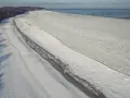 Zamarznięta plaża i Bałtyk, jakby czas się zatrzymał od kiedy powstało morze bałtyckie. W oddali widać statki.