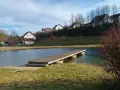 Holzsteg am Badesee Forchheim, mit Häusern im Hintergrund und einem Spielplatz.