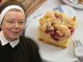 Siostra z uśmiechem prezentuje wilgotne ciasto ucierane ze śliwkami, posypane kruszonką.