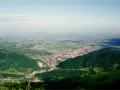 Vista panoramica dalla sella di Fadalto su una vasta pianura punteggiata di case e campi, con colline verdi in primo piano.