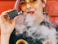 Joven con vaper exhala humo. ¿Cuántas calorías tiene un vaper? La respuesta es cero, ya que no contiene azúcares ni grasas.