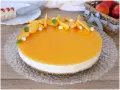 Delizioso cheesecake alle pesche con glassa lucida e fette di pesca fresca, guarnito con menta e piccole meringhe.