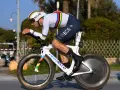 A cyclist in a rainbow jersey races a time trial bike, pushing hard during the Tour de France.