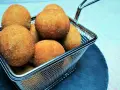 Croquetas doradas y crujientes en una cesta metálica.