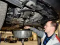 Mechanik spuszcza olej z silnika samochodu. Regularna wymiana oleju to klucz do długowieczności auta.