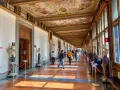 Korytarz galerii sztuki we Florencji z rzeźbami, obrazami i malowanym sufitem.