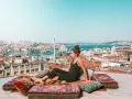 A woman enjoys a drink on a rooftop overlooking Istanbul, a scene straight out of a Rick Steves Turkey adventure.