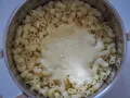 Gęsty, kremowy sos serowy otula makaron w garnku, tworząc pyszny makaron mac and cheese.