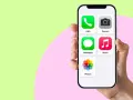En hand håller en iPhone 13 med ikoner för samtal, meddelanden, kamera, musik och foton.